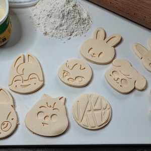 Peut inclure: Huit emporte-pièces sur une planche à découper blanche. Les emporte-pièces sont en forme de lapin, de chat, de renard, de hérisson, de chien, de rond avec des lignes et de deux formes différentes de chat.