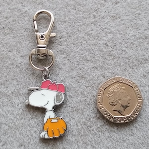 May include: A silver keychain with a cartoon character wearing a red baseball cap and holding a baseball glove. The character is white with black eyes and a black nose. The keychain is attached to a silver ring.