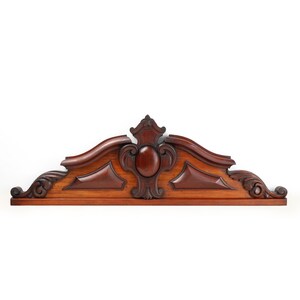 May include: A carved wooden headboard with a decorative design featuring a central oval shape and intricate scrollwork. The headboard is made of dark mahogany wood and has a rich, warm color.