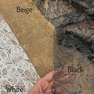 A hand is holding a piece of fabric with three different colored floral patterns on it, labeled as "Beige", "Black", and "White".