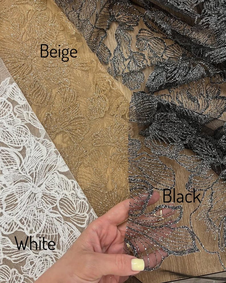 A hand is holding a piece of fabric with three different colored floral patterns on it, labeled as "Beige", "Black", and "White".