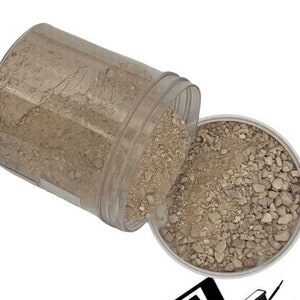 May include: A clear plastic container filled with light brown gravel. The container is tipped over, spilling the gravel onto a white surface. The container has a label that reads "ROCK-N-WOOD SUPPLY YARD".