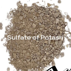 May include: A close-up of a pile of brown sulfate of potash fertilizer. The fertilizer is a granular material and is commonly used to improve soil health.