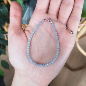 May include: A delicate bracelet made with light blue gemstone beads and a silver clasp.