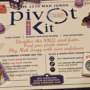 May include: A white instructional card for the 2020 Mah Jongg Pivot Kit featuring blue and red text, surrounded by small colorful frog-shaped figurines and Mah Jongg tiles. The card includes text about tracking hands, identifying patterns, and strategy.