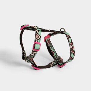 Peut inclure: Un harnais pour chien à motif vert, rose et marron avec des boucles en plastique rose.