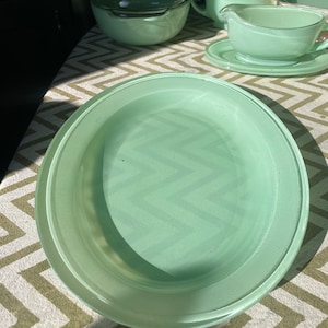May include: A light green oval-shaped serving dish with a raised rim. The dish is made of glass and has a smooth, glossy finish.