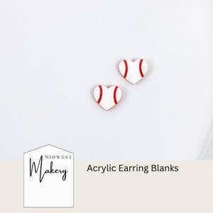May include: Two heart-shaped acrylic earring blanks. Each blank is white with red stitching, resembling a baseball. The text "Acrylic Earring Blanks" is visible.