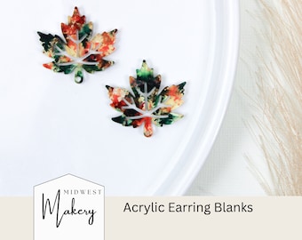 May include: Two acrylic maple leaf earring blanks with a watercolor-like design in shades of red, green, and yellow. The blanks are on a white surface. Midwest Makery Acrylic Earring Blanks.