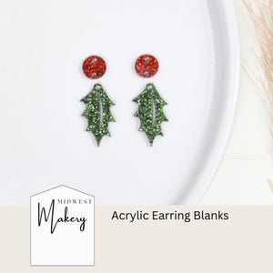 May include: Two green glitter holly leaf shaped acrylic earring blanks with red glitter earring backs.  The blanks are on a white surface.  Midwest Makery Acrylic Earring Blanks.