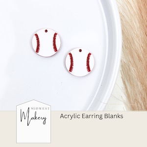 Könnte beinhalten: Zwei weiße Acryl-Ohrringrohlinge in Form von Baseballs mit roten Nähten. Die Rohlinge liegen auf einem weißen Teller. Der Text "Midwest Makery" und "Acrylic Earring Blanks" ist unter dem Teller sichtbar.