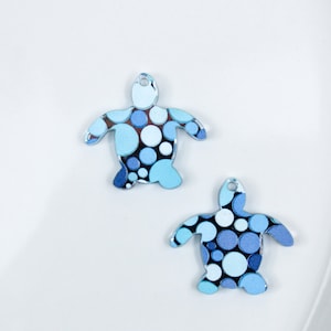 May include: Two blue and white patterned turtle charms with a circle design.