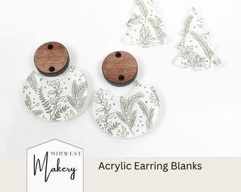 May include: Acrylic earring blanks with a botanical design. The earrings have a wooden top and a semi-circle bottom with a white background and green floral pattern. Two Christmas tree-shaped blanks are also visible. The text "Midwest Makery" and "Acrylic Earring Blanks" are present.