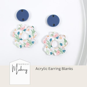 Può includere: Due paia di orecchini in acrilico con un motivo floreale e un foro rotondo al centro. I paia di orecchini sono su una superficie bianca con due paia di orecchini rotondi blu.