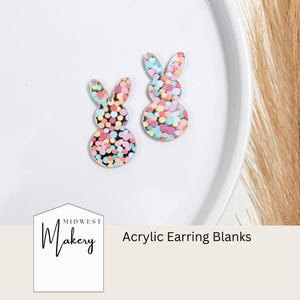 May include: Two pastel colored acrylic bunny shaped earring blanks with a confetti pattern. The blanks are on a white plate. The text "Midwest Makery" and "Acrylic Earring Blanks" are visible below the plate.