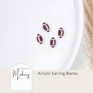 May include: Four brown and white football-shaped acrylic earring blanks on a white plate. The text "Midwest Makery" and "Acrylic Earring Blanks" is visible below the plate.
