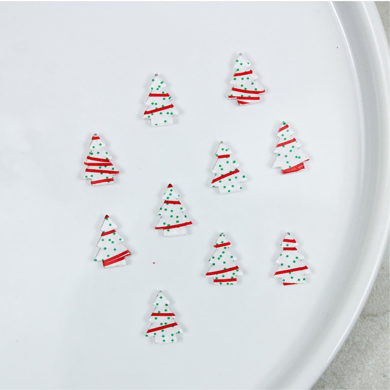 K&ouml;nnte beinhalten: Zehn wei&szlig;e Weihnachtsbaumschmuckst&uuml;cke mit roten und gr&uuml;nen Designs. Die Schmuckst&uuml;cke sind in einem Kreis auf einer wei&szlig;en Oberfl&auml;che angeordnet.