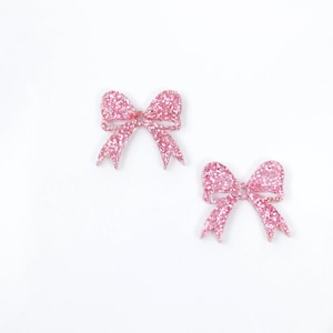 May include: Two pink glitter bows with a white background.