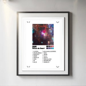 Op de afbeelding: Een ingelijste poster van het Duki-album Antes de Ameri. Het kunstwerk toont een kleurrijke nevel met een centrale planeet en een rode laserstraal. Daaronder staat de tracklist met 16 nummers en een kleurenpalet van zwarte, rode, paarse en blauwe vierkanten.