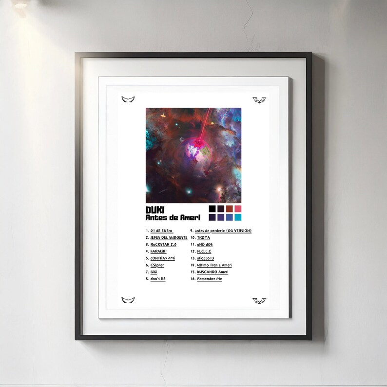 Op de afbeelding: Een ingelijste poster van het Duki-album Antes de Ameri. Het kunstwerk toont een kleurrijke nevel met een centrale planeet en een rode laserstraal. Daaronder staat de tracklist met 16 nummers en een kleurenpalet van zwarte, rode, paarse en blauwe vierkanten.