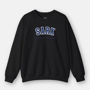 May include: Black sweatshirt with a blue and white graphic print that says "SARK CHANNEL ISLANDS".