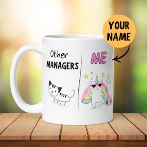 Può includere: Una tazza da caffè bianca con un'illustrazione in bianco e nero di un gatto sul lato sinistro e il testo "Other Managers". Sul lato destro c'è un'illustrazione colorata di un gatto con un corno di unicorno e occhiali da sole, con il testo "ME" sopra. Il testo "YOUR NAME" è scritto su un cerchio giallo.