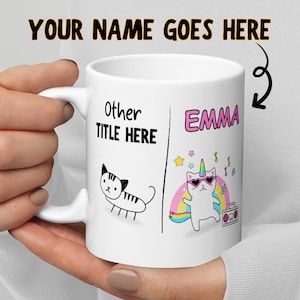 May include: White ceramic mug with a black and white drawing of a cat on one side and a colorful illustration of a cat with a unicorn horn and sunglasses on the other side. The text "Other Title Here" is on the left side and "Emma" is on the right side.