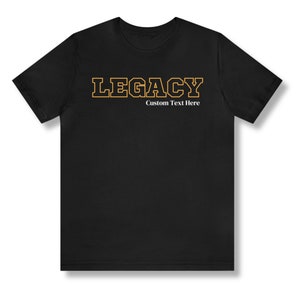 May include: Black t-shirt with the word "LEGACY" in orange outlined letters. The text "Custom Text Here" is printed in white below the word "LEGACY".