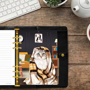 May include: A white and brown cat is curled up under a blanket in a room with a clock on the wall. The cat is looking at the camera. The image is a planner page with a cat illustration.