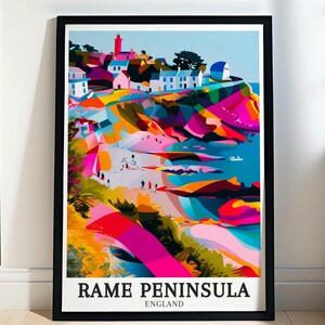 May include: A framed art print of Rame Peninsula, England, featuring a colorful, abstract landscape. The artwork showcases a coastal scene with buildings, a lighthouse, and vibrant hues of pink, blue, and yellow. The print is in a black frame.