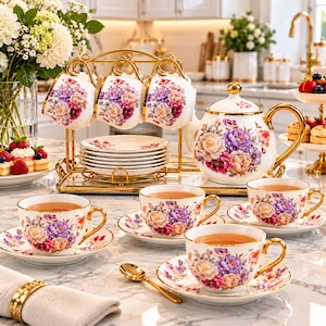 May include: A white porcelain tea set featuring a vibrant floral pattern of purple, pink, and orange peonies with gold-trimmed edges. The set includes a teapot, multiple teacups with matching saucers, and a gold metal stand holding three cups.
