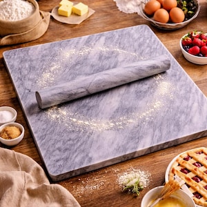 Puede incluir: Una tabla de repostería de mármol gris con un rodillo a juego, rodeada de ingredientes para hornear. También se ven un cuenco pequeño con bayas, huevos, mantequilla, harina y una tarta parcialmente horneada. Tema de repostería.