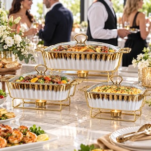 Könnte beinhalten: Drei rechteckige weiße Keramik-Buffetwärmer mit goldfarbenen Rändern und Deckeln, die jeweils auf einem goldfarbenen Metallständer mit einem darunter platzierten Teelicht stehen. Die Schalen enthalten zubereitete Speisen.