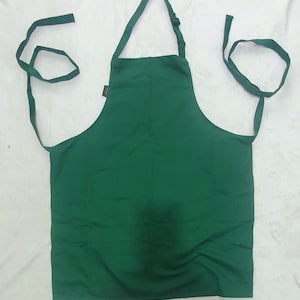 May include: A dark green apron with adjustable neck straps and two long ties. The apron has a single pocket on the front.