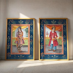 May include: Two framed art prints featuring detailed illustrations of figures in traditional attire. The frames are gold with a dark blue border adorned with floral patterns. The artwork depicts individuals in colorful, patterned clothing, set against a backdrop of a window and floral arrangements.