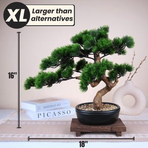 May include: An XL artificial bonsai tree, approximately 16 inches tall and 18 inches wide, with vibrant green foliage and a textured brown trunk. The bonsai sits in a black ceramic pot on a wooden stand. The image includes the text "Larger than alternatives".