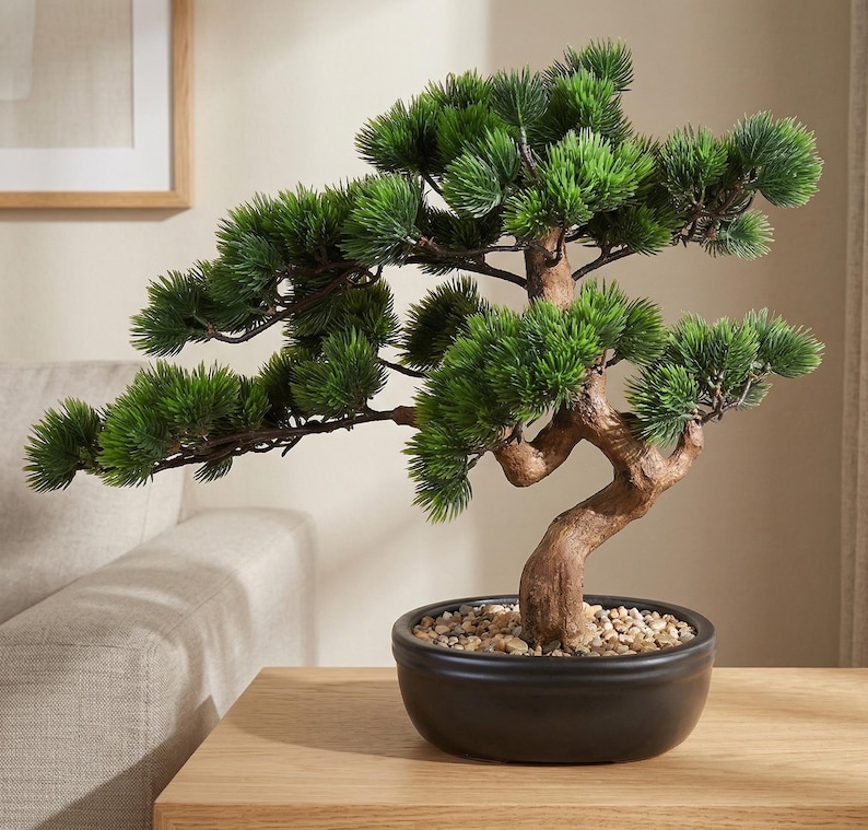 May include: A small, artificial bonsai tree in a black ceramic pot. The tree has vibrant green foliage and a brown, curved trunk. The pot is filled with small, light-colored pebbles. The bonsai is displayed on a light-colored wooden surface.