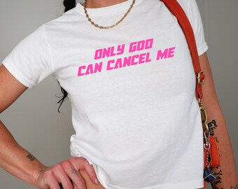 Op de afbeelding: Wit T-shirt met roze tekst die "Only God Can Cancel Me" zegt.