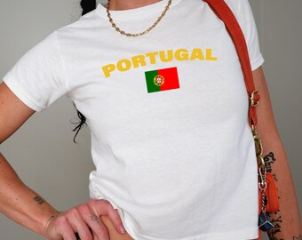 May include: White t-shirt with the word "PORTUGAL" in yellow letters and a small image of the Portuguese flag.