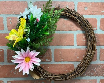 A simple grapevine wreath adorned with spring flowers.