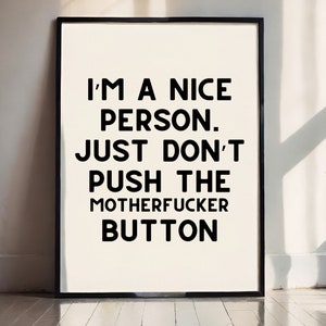 May include: A framed print with the text: "I'M A NICE PERSON. JUST DON'T PUSH THE MOTHERFUCKER BUTTON" in black, bold font on a white background. The frame is black.