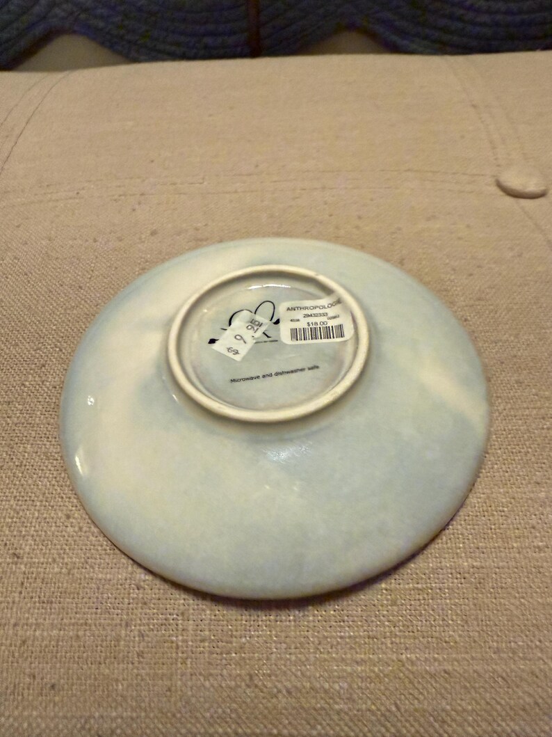 May include: A set of three ceramic mugs with a speckled, cream-colored glaze. Each mug features a different hand-painted floral design in shades of blue, green, and yellow. The mugs have a simple, rounded shape and a comfortable handle.