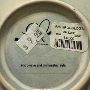 May include: A white ceramic mug with a black handle and the text "But First, Coffee" in a handwritten style. The mug is on a white surface. The mug is approximately 4 inches tall.