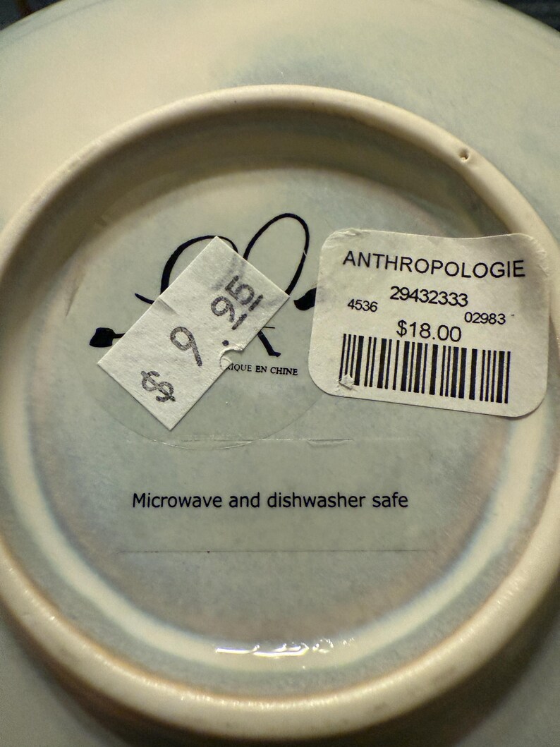 May include: A white ceramic mug with a black handle and the text "But First, Coffee" in a handwritten style. The mug is on a white surface. The mug is approximately 4 inches tall.