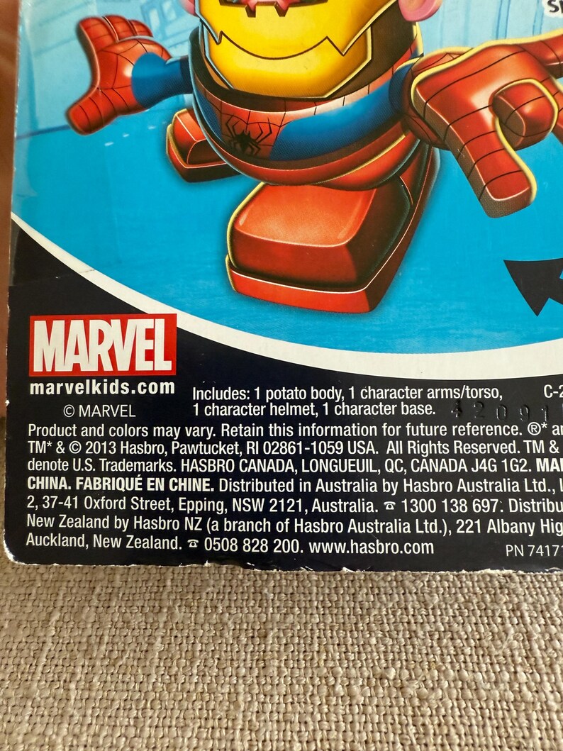 Może przedstawiać: Zabawka Mr. Potato Head z motywem Marvela, inspirowana Spider-Manem. Zabawka ma czerwoną i niebieską kolorystykę, z ż&oacute;łtym hełmem. Opakowanie zawiera logo Marvel i tekst "marvelkids.com". Zawiera korpus, ramiona/tuł&oacute;w, hełm i podstawę.