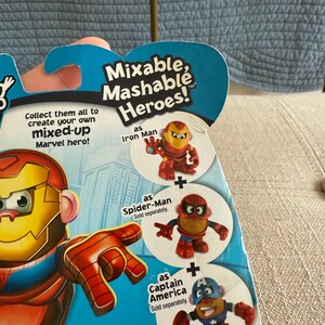 Może przedstawiać: Opakowanie z zabawkami Mixable, Mashable Heroes! z Iron Manem, Spider-Manem i Kapitanem Ameryką. Opakowanie zawiera tekst "Zbierz je wszystkie, aby stworzyć własnego, zmiksowanego bohatera Marvela!" i "W zależności od dostępności."