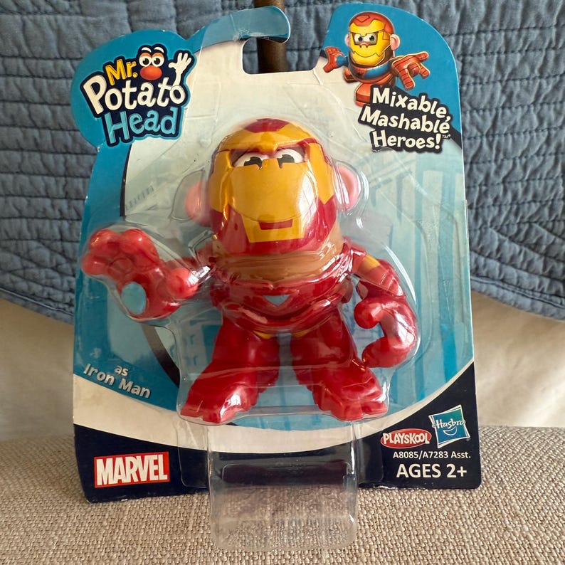 Może przedstawiać: Pan Głowacki jako Iron Man, czerwono-ż&oacute;łta figurka zabawki w oryginalnym opakowaniu. Opakowanie zawiera logo Marvel i tekst &bdquo;Mixable Mashable Heroes!&rdquo;. Zabawka jest polecana dla dzieci w wieku od 2 lat.