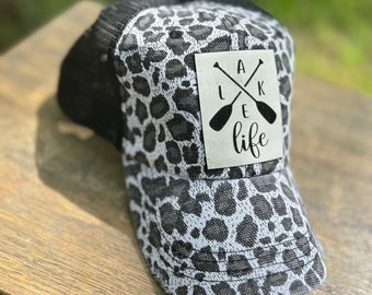 Casquette trucker effet vieillie à imprimé léopard Lake Life avec écusson gravé en similicuir. Casquette trucker noire grise vintage effet vieilli.