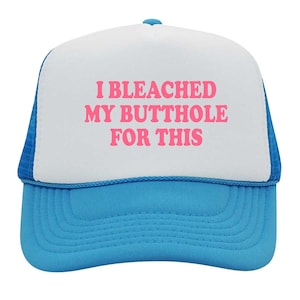 May include: A blue and white trucker hat with the text "I BLEACHED MY BUTTHOLE FOR THIS" in pink. The hat has a white front panel, a blue brim, and a blue mesh back.