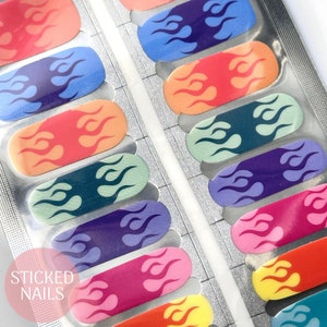 May include: A sheet of colourful nail wraps featuring a flame design. The wraps are arranged in rows and are ready to be applied to nails. The brand name "STICKED NAILS" is visible in the bottom left corner.